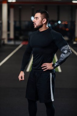 Siyah giysiler içinde spor salonunda kameraya poz büyük kaslar, yakışıklı adamla