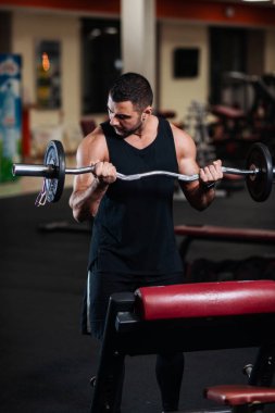 Bir adam pazı salonunda eğitiyor. Bir halter alıştırmalar yapan kaslı vücut geliştirmeci adam.