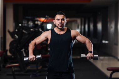 Deltoid halter salonunda ile omuz kasları için egzersiz yaparak yakışıklı vücut geliştirmeci