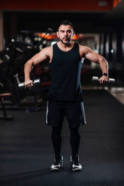 Deltoid halter salonunda ile omuz kasları için egzersiz yaparak yakışıklı vücut geliştirmeci