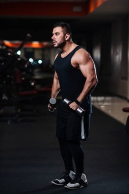 Deltoid halter salonunda ile omuz kasları için egzersiz yaparak yakışıklı vücut geliştirmeci