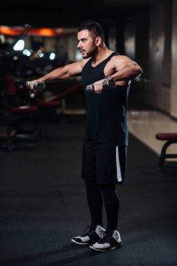 Deltoid halter salonunda ile omuz kasları için egzersiz yaparak yakışıklı vücut geliştirmeci