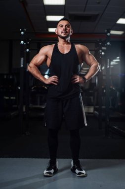 Poz, kasları spor salonunda kapalı gösteren güzel atletik erkek