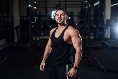 Poz, kasları spor salonunda kapalı gösteren güzel atletik erkek