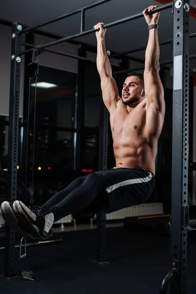 Acımasız atletik adam bar salonunda asılı karın kaslarının trenler
