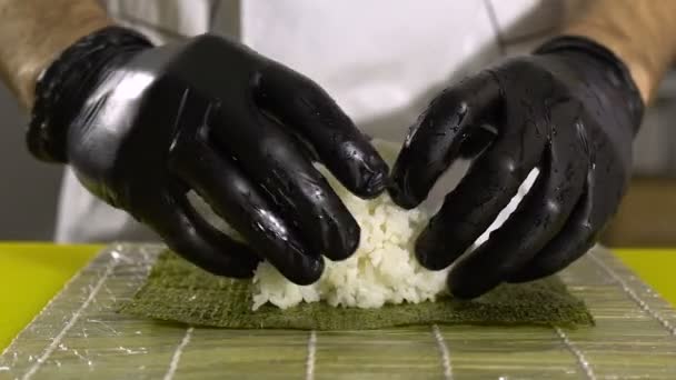 As mãos do chef preparam a comida japonesa, o cozinheiro faz o sushi, prepara o rolo de sushi, põe o arroz na base — Vídeo de Stock