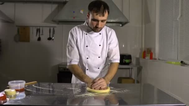 Готовить на кухне готовит круглый хлебный продукт, вращая и разминая руки — стоковое видео
