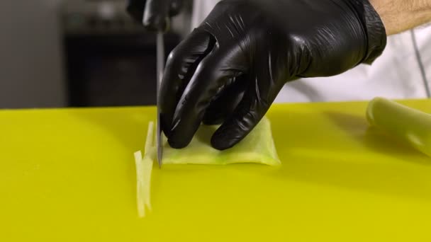 Kokki leikkaa kurkkukerroksen pois leikatakseen sen sushirullien täytteenä — kuvapankkivideo