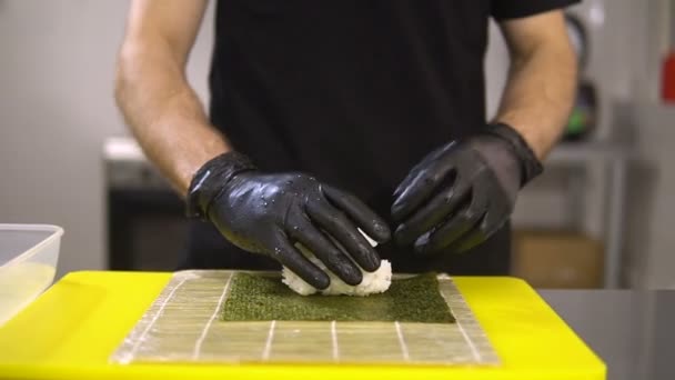 As mãos do chef preparam a comida japonesa, o cozinheiro faz o sushi, prepara o rolo de sushi, põe o arroz na base — Vídeo de Stock