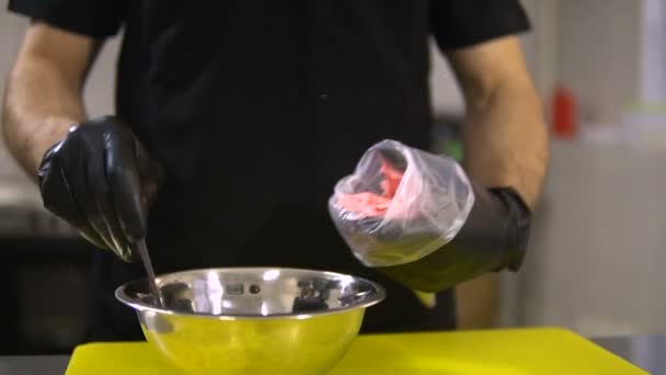 Человек кладет мороженое в стакан с ложкой на кухне — стоковое видео