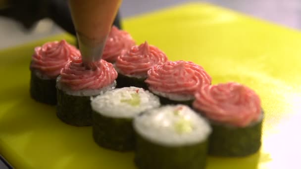 Mains du chef cuisinier plats japonais, le chef fait des sushis, prépare le rouleau de sushi, verse la crème — Video