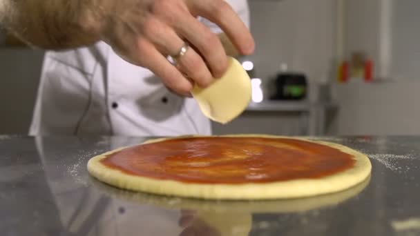 Chef de mão coloca queijo na base de pizza em molho de tomate close-up — Vídeo de Stock