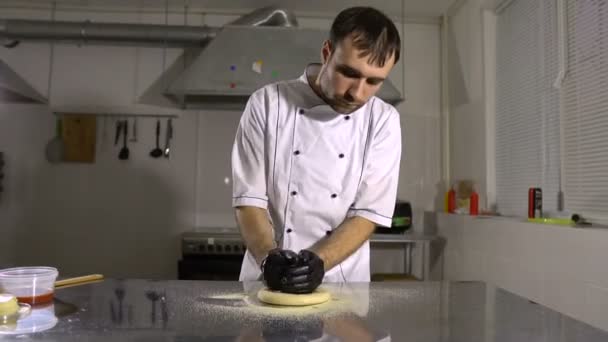 Готовить на кухне готовит круглый хлебный продукт, вращая и разминая руки — стоковое видео