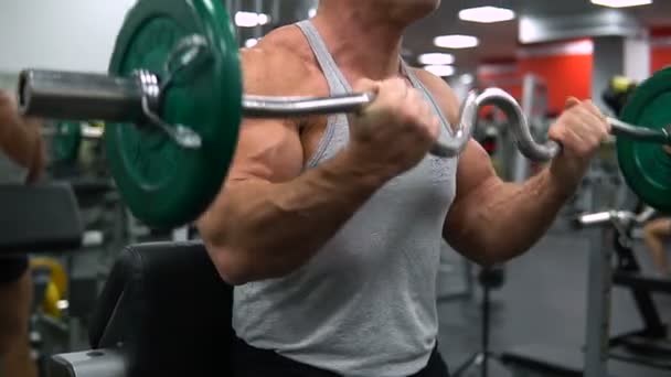 RUSIA, TOGLIATTI - 20 DE SEPTIEMBRE DE 2018: Hombre entrena bíceps con una barra en el gimnasio — Vídeo de stock