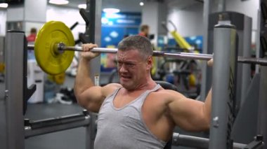 Rusya, Togliatti - 20 Eylül 2018: Kaslı adam onun omuz ile bir halter salonunda eğitiyor. Sağlık ve fitness kavramı