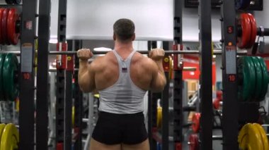 Rusya, Togliatti - 20 Eylül 2018: Kaslı adam onun omuz ile bir halter salonunda eğitiyor. Sağlık ve fitness kavramı