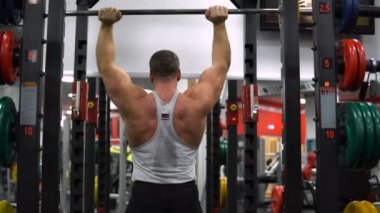 Rusya, Togliatti - 20 Eylül 2018: Kaslı adam onun omuz ile bir halter salonunda eğitiyor. Sağlık ve fitness kavramı