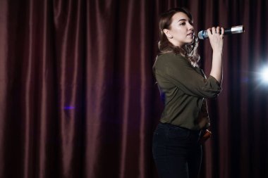 Bir kadının kırmızı perdeler arka plan üzerinde mikrofon karaoke sahnede şarkı