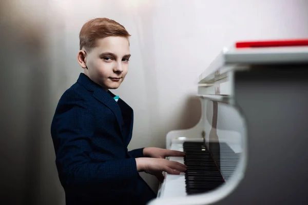 Çocuk piyano çalıyor. Şık çocuk bir müzik aleti çalmayı öğrenir