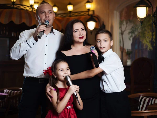 Family karaoke. Portrait of a happy family, singing in microphones in the restaurant