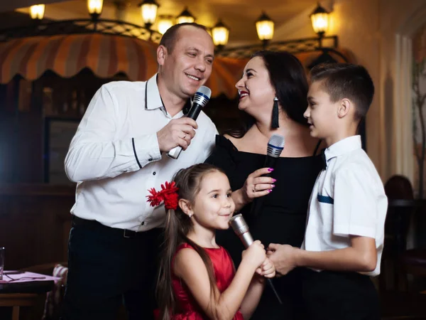 Family karaoke. Portrait of a happy family, singing in microphones in the restaurant