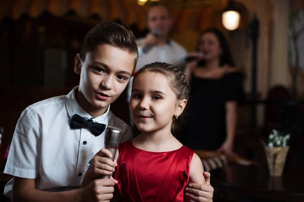 Küçük kız ve erkek kardeşim karaoke mikrofon şarkı ve ailelerini arkada şarkı