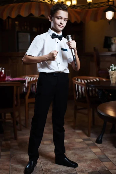 Bir restoranda mikrofona bir beyaz gömlek şarkı bir çocuk. Bebek karaoke.
