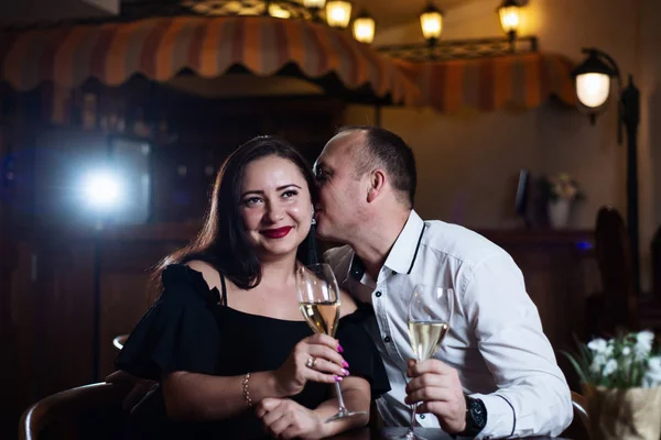 Adult man and woman on a date in a restaurant holding champagne in their hands