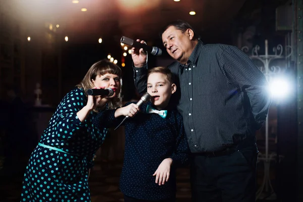 Family karaoke. Portrait of a happy family, singing in microphones in the restaurant