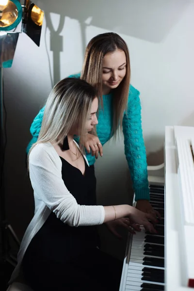 两个年轻美丽的女孩弹钢琴 女孩学习演奏乐器 — 图库照片