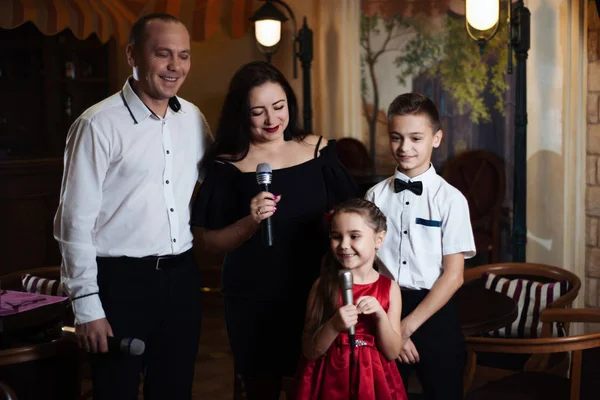 Family karaoke. Portrait of a happy family, singing in microphones in the restaurant