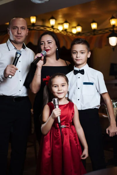 Family karaoke. Portrait of a happy family, singing in microphones in the restaurant