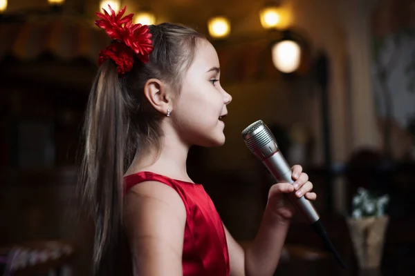 Kız mikrofon ile. Küçük bir çocuk karaoke closeup şarkı söylüyor.