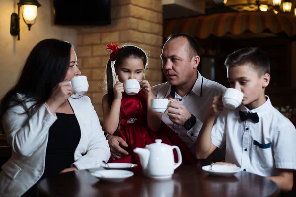 Family came together in a cafe. Mom, dad, little daughter and son drink tea. They are happy together. Happy family lunch concept.