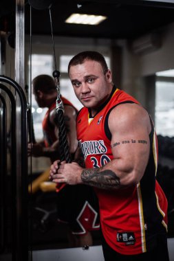 Rusya, Samara - 18 Aralık 2018: spor salonunda bir egzersiz sırasında büyük kaslı adam triceps dumbbells ile trenler