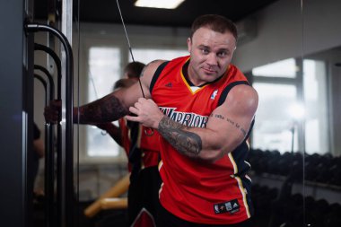 Rusya, Samara - 18 Aralık 2018: spor salonunda bir egzersiz sırasında büyük kaslı adam triceps dumbbells ile trenler