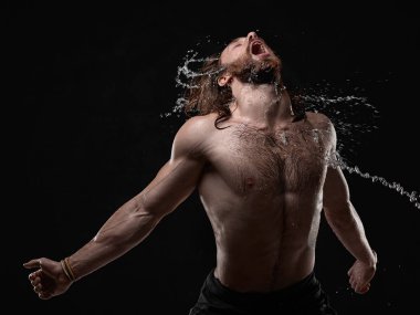 Gömleksiz yakışıklı genç adam su ile poz yüz ve göğüs Studio çekimde su sıçramalarına