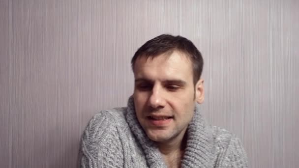 Man med grå tröja, frossa från kyla och hosta hemma på vägg bakgrund — Stockvideo