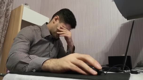 Young man working on his laptop and wipes his eyes from fatigue — Stock Video