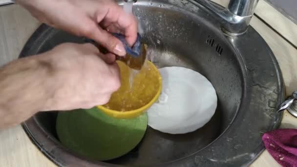 Las manos de los hombres de la casa lavan los platos bajo el agua corriente de cerca — Vídeos de Stock