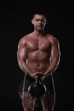 Yakışıklı genç trenler dumbbells ile su sıçramalarına yüzünde ve göğüs Studio atış ile