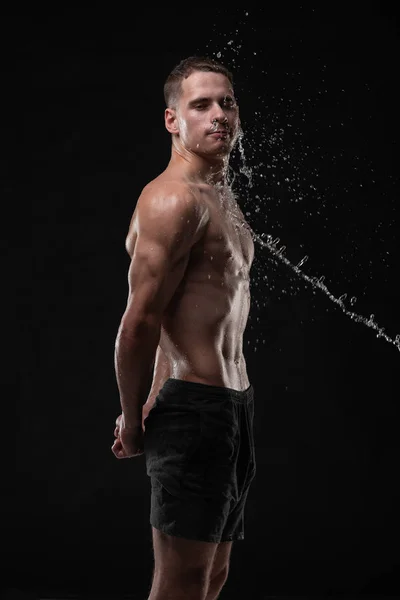 Guapo joven posando con salpicaduras de agua en la cara y el pecho en Studio shot —  Fotos de Stock