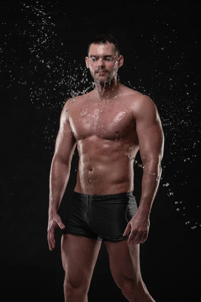 Knappe jongeman poseren met water spatten op gezicht en borst in Studio schot Stockfoto