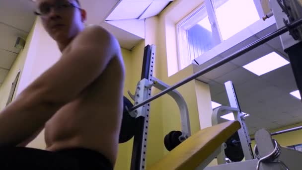 Junger muskulöser Mann beim Bankdrücken. Mann beginnt im Fitnessstudio mit einer Langhantel zu trainieren — Stockvideo