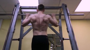 Genç adam spor salonunda fitness meşgul. Atlet barda çekildi