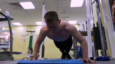 Genç spor adam spor salonunda şınav gerçekleştirir. Atlet Fitness meşgul