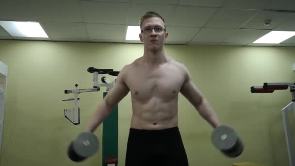 Νέος άνθρωπος εκπαιδεύει τους ώμους του με βαράκια στο γυμναστήριο — Αρχείο Βίντεο