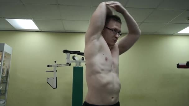 Man stretching arm innan gym träning. Fitness stark manliga idrottare stående inomhus uppvärmning. — Stockvideo