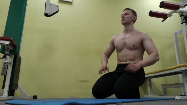 Człowiek, odpoczynek w siłowni. Fitness silne lekkoatletka mężczyzna siedzący w pomieszczeniu rozgrzewanie — Wideo stockowe