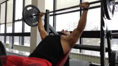 Bench Press genç kaslı adam. Adam spor salonunda bir halter ile trenler